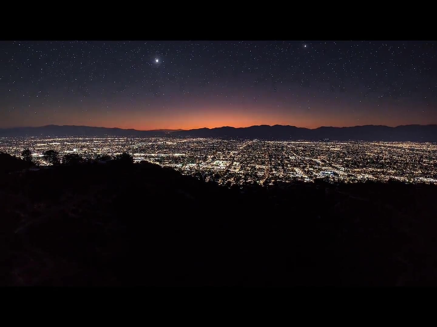 A cinematic overhead still of canyon and city adjacency.